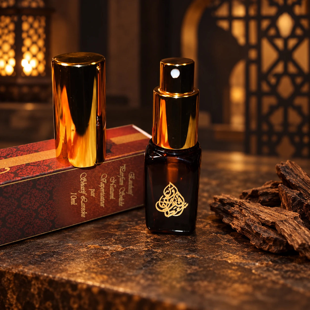 Ambergris Al Oud 10ml perfume spray, black bottle with gold atomizer and cap, original box and agarwood in a dark Oriental setting.