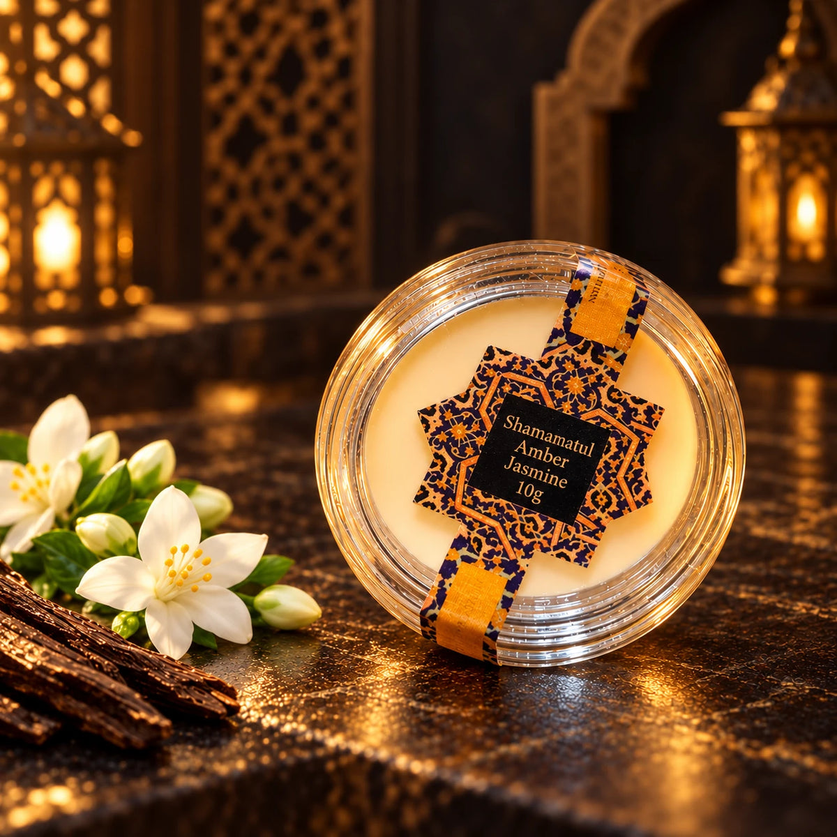 Shamamatul Amber Jasmine 10g solid cream perfume in a labelled round transparent pot with jasmine flowers in a dark Oriental setting.